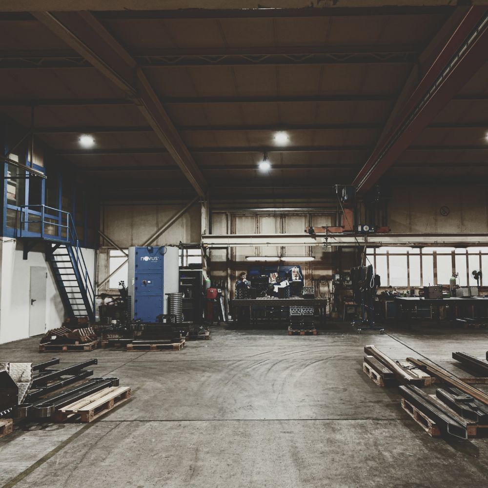 Produktionshalle bei CUTMETALL mit Paletten voll Recyclingmaschinen-Komponenten wie Siebträgern und Verschleißteilen