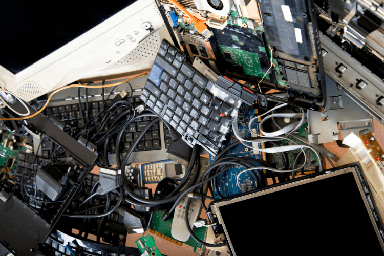 Ein chaotischer Haufen Elektroschrott mit alten Tastaturen, Kabeln, Platinen, Bildschirmen und weiteren elektronischen Bauteilen.