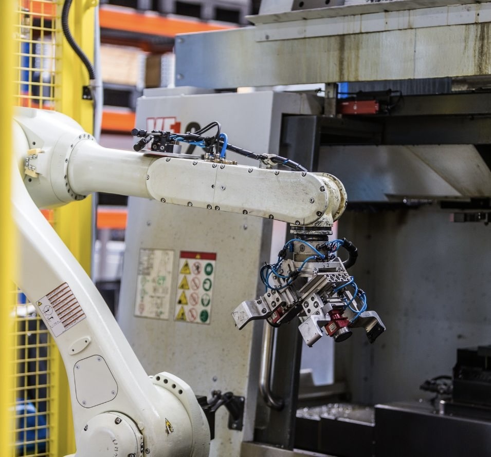 Macchina bianca nella nostra officina di produzione. Sullo sfondo si vedono scaffali con ricambi ottimizzati come controlame, vagli, lame del rotore, lame dello statore, corone di taglio e altro.